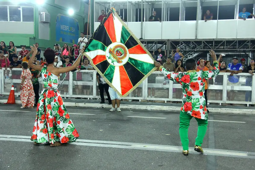 Casal de mestre-sala e porta bandeira com as cores da escola 